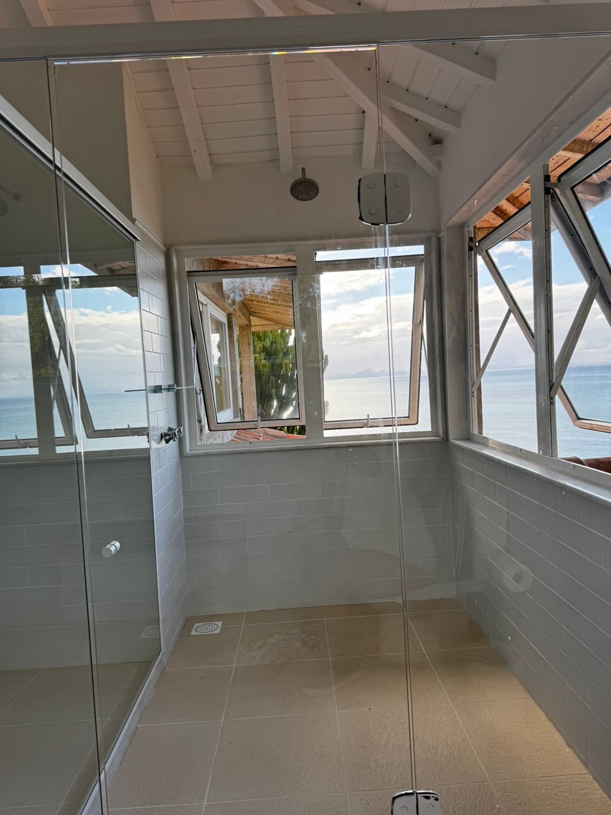 Banho com chuveiro e janelas para o mar