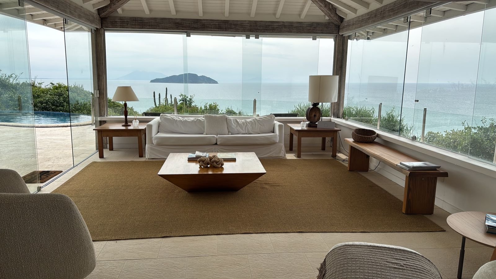 Living integrado com paredes de vidro e vista para as ilhas