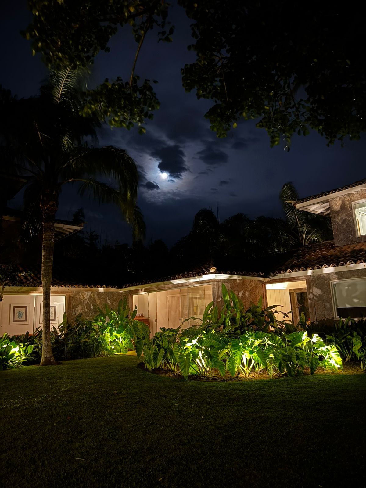 Fachada e jardim iluminados à noite sob o luar