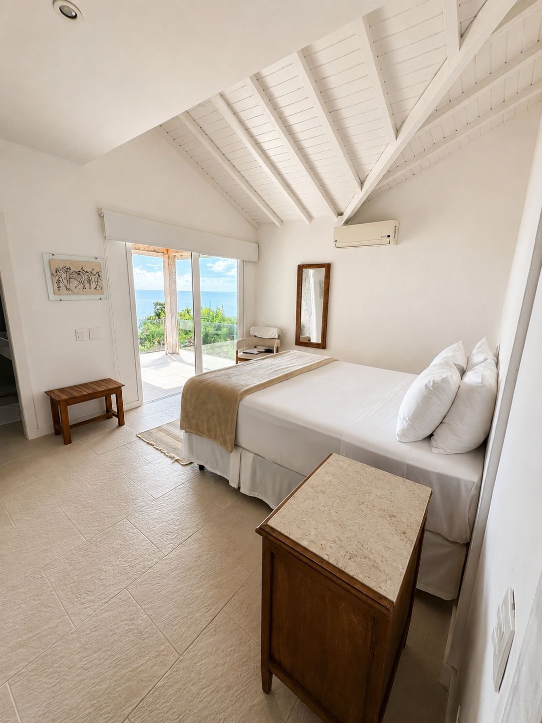 Suíte com cama de casal e varanda sobre o mar